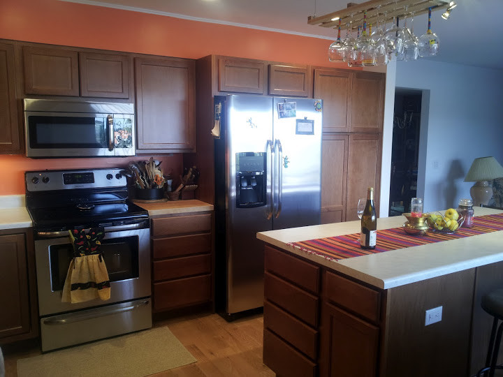 Cette photo montre une cuisine chic en L et bois brun de taille moyenne avec un évier 2 bacs, un électroménager en acier inoxydable et parquet clair.