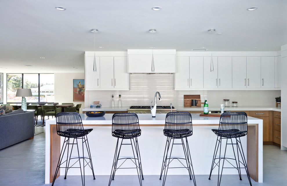 1950s l-shaped gray floor open concept kitchen photo in Orange County with flat-panel cabinets, white cabinets, white backsplash, paneled appliances, an island and white countertops