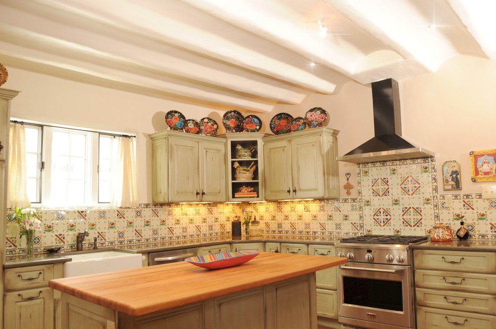 Inredning av ett amerikanskt avskilt, mellanstort u-kök, med en rustik diskho, luckor med upphöjd panel, gröna skåp, bänkskiva i koppar, flerfärgad stänkskydd, stänkskydd i mosaik, rostfria vitvaror, en köksö och klinkergolv i terrakotta