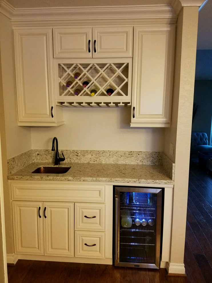 Inredning av ett modernt mellanstort kök, med en undermonterad diskho, luckor med profilerade fronter, vita skåp, granitbänkskiva, rostfria vitvaror och mellanmörkt trägolv