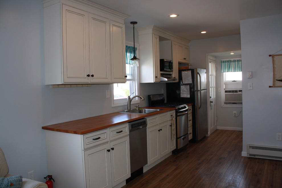 Photo of a small nautical single-wall open plan kitchen in Philadelphia with a built-in sink, flat-panel cabinets, white cabinets, wood worktops, stainless steel appliances, medium hardwood flooring and no island.