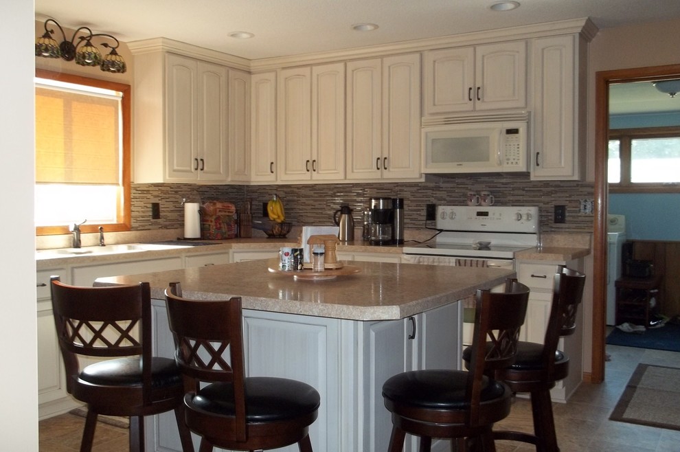 Photo of a traditional kitchen in Minneapolis with white cabinets, laminate countertops, beige splashback, white appliances, lino flooring and an island.