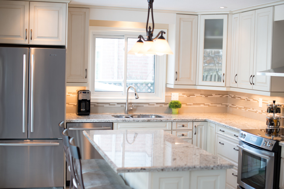 Classic kitchen in Toronto with a double-bowl sink, raised-panel cabinets, white cabinets, granite worktops, beige splashback, glass tiled splashback, stainless steel appliances, vinyl flooring and an island.