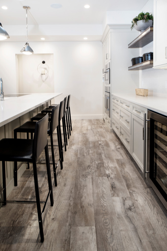 Mid-sized transitional single-wall vinyl floor and brown floor eat-in kitchen photo in Other with an undermount sink, quartzite countertops, white backsplash, stainless steel appliances, an island, shaker cabinets, gray cabinets and porcelain backsplash