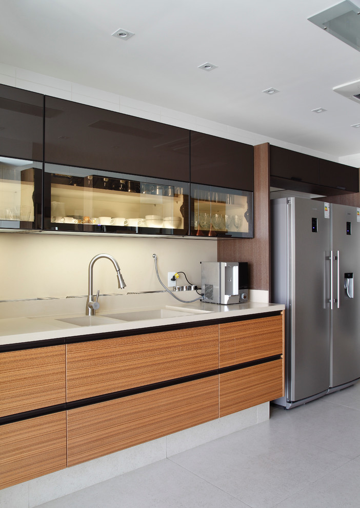 Große Moderne Küche mit flächenbündigen Schrankfronten, hellbraunen Holzschränken und Küchengeräten aus Edelstahl in Sonstige