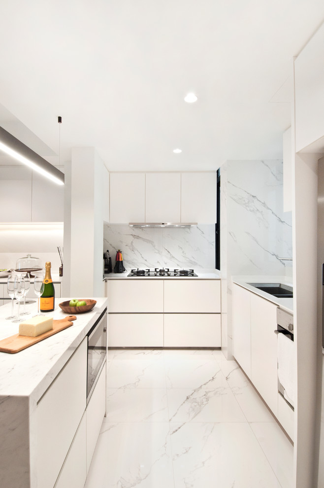 Photo of a contemporary l-shaped open plan kitchen in Singapore with a submerged sink, flat-panel cabinets, white cabinets, marble worktops, white splashback, marble splashback, black appliances, marble flooring, an island and white floors.