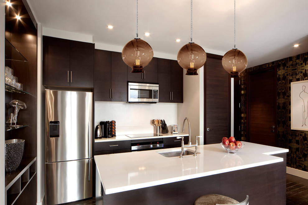 Moderne Küche mit Unterbauwaschbecken, flächenbündigen Schrankfronten, dunklen Holzschränken, Küchenrückwand in Weiß, Küchengeräten aus Edelstahl, Kücheninsel und Tapete in New York