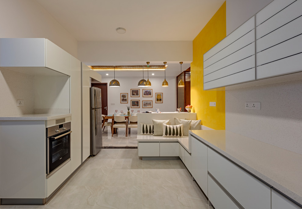 Imagen de cocinas en U actual de tamaño medio cerrado con puertas de armario blancas, electrodomésticos de acero inoxidable y suelo beige