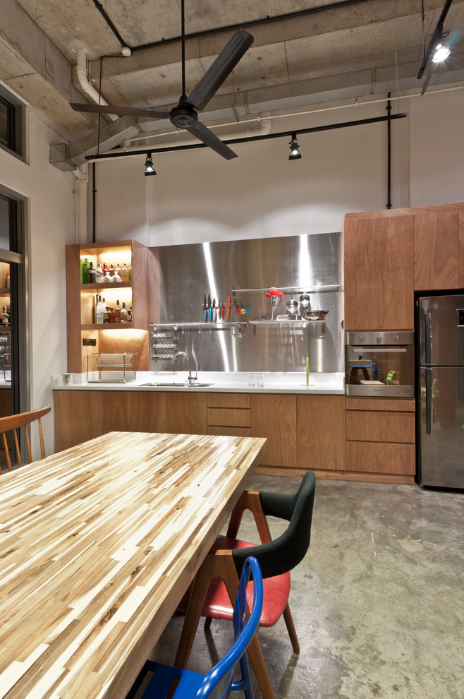 Immagine di una cucina abitabile industriale con ante lisce, ante in legno bruno, paraspruzzi a effetto metallico, paraspruzzi con piastrelle di metallo e elettrodomestici in acciaio inossidabile