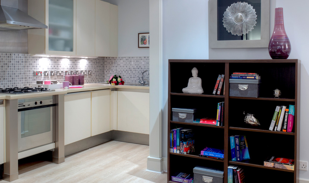 Moderne Wohnküche in L-Form mit flächenbündigen Schrankfronten, weißen Schränken, Mineralwerkstoff-Arbeitsplatte, Küchenrückwand in Grau, Rückwand aus Mosaikfliesen und Küchengeräten aus Edelstahl in London