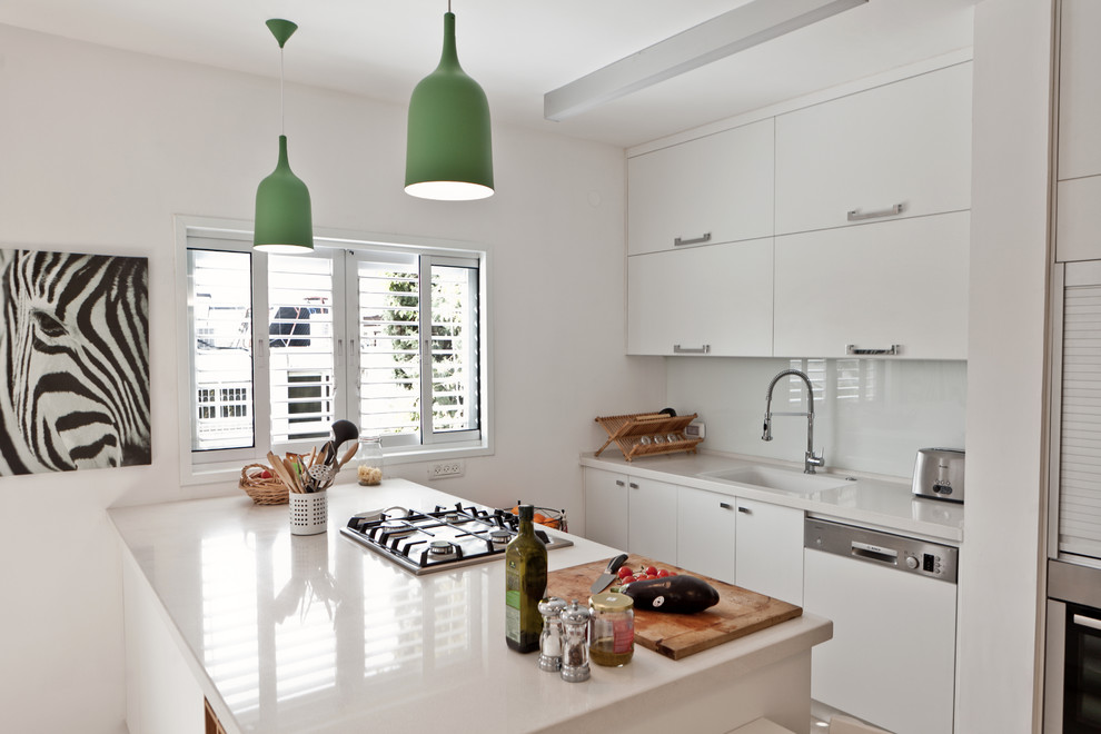 Idée de décoration pour une cuisine parallèle design avec un placard à porte plane, des portes de placard blanches, une crédence blanche, une crédence en feuille de verre et un électroménager blanc.