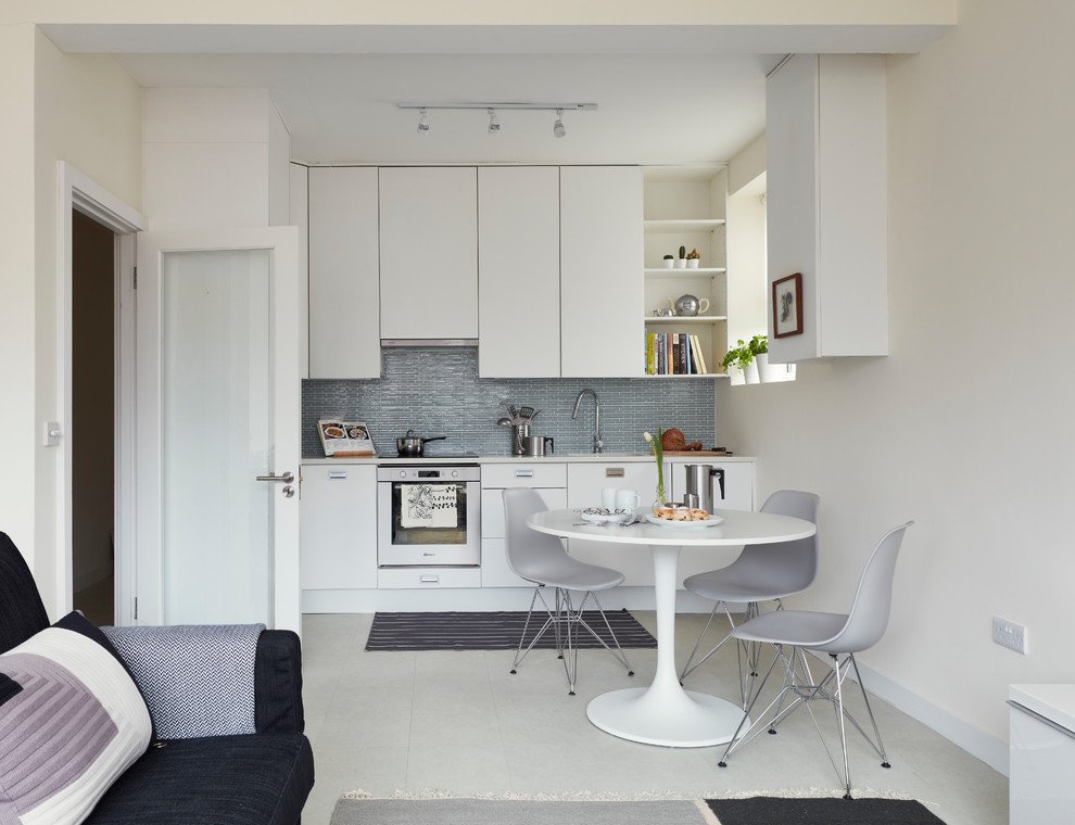 Photo of a small scandinavian l-shaped open plan kitchen in Dublin with a submerged sink, flat-panel cabinets, white cabinets, quartz worktops, green splashback, glass tiled splashback, stainless steel appliances, vinyl flooring, no island, white floors and white worktops.