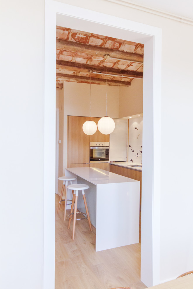 バルセロナにあるお手頃価格の中くらいな北欧スタイルのおしゃれなキッチン (アンダーカウンターシンク、フラットパネル扉のキャビネット、中間色木目調キャビネット、白いキッチンパネル、シルバーの調理設備、淡色無垢フローリング) の写真