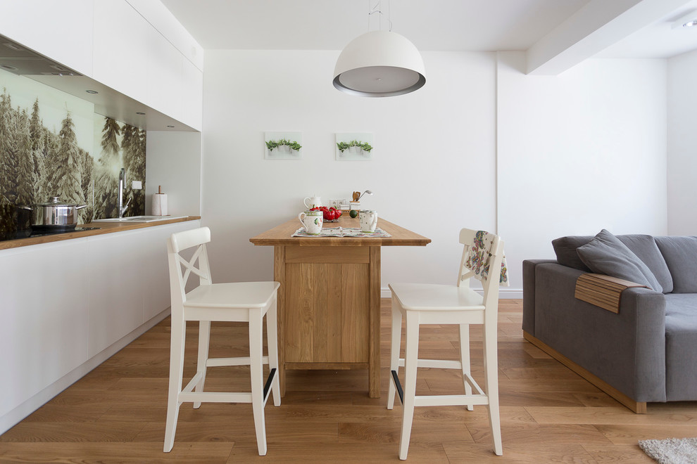 Свежая идея для дизайна: прямая кухня-гостиная в скандинавском стиле с плоскими фасадами, белыми фасадами, деревянной столешницей, разноцветным фартуком, паркетным полом среднего тона и полуостровом - отличное фото интерьера