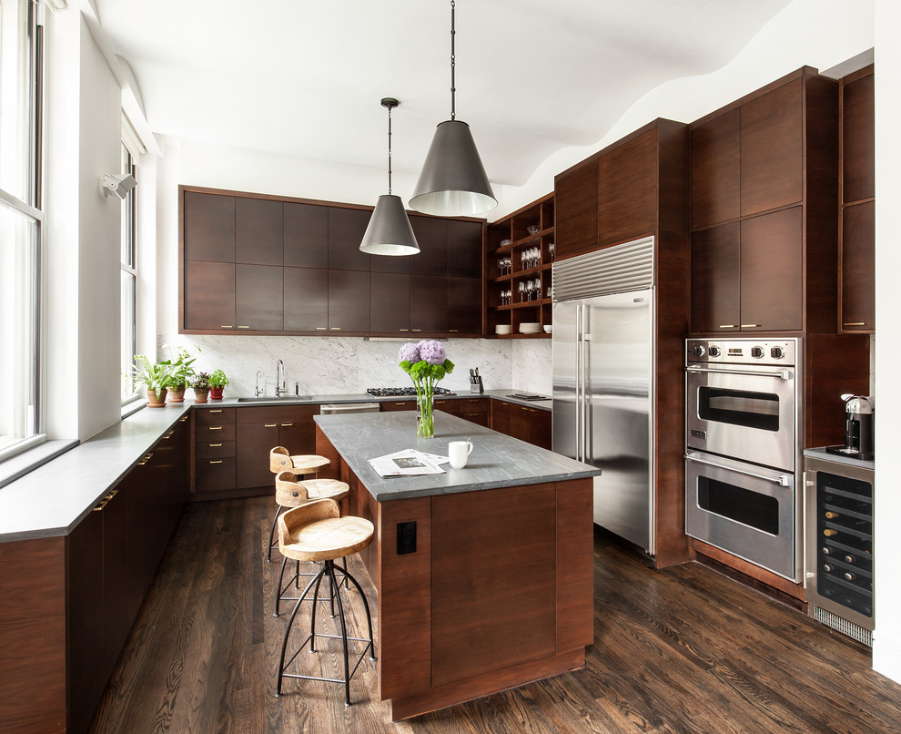 Modern inredning av ett stort u-kök, med en undermonterad diskho, släta luckor, skåp i mörkt trä, bänkskiva i täljsten, vitt stänkskydd, stänkskydd i marmor, rostfria vitvaror, en köksö, brunt golv och mörkt trägolv