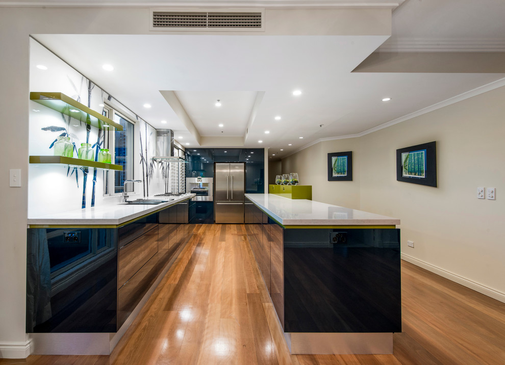 Zweizeilige, Mittelgroße Moderne Wohnküche mit Waschbecken, flächenbündigen Schrankfronten, blauen Schränken, Quarzwerkstein-Arbeitsplatte, Küchenrückwand in Weiß, Glasrückwand, Küchengeräten aus Edelstahl, braunem Holzboden und Kücheninsel in Brisbane