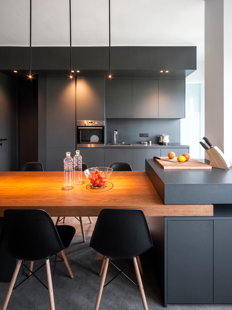 Immagine di una cucina minimal di medie dimensioni con lavello da incasso, ante lisce, paraspruzzi grigio, elettrodomestici in acciaio inossidabile, penisola e pavimento grigio