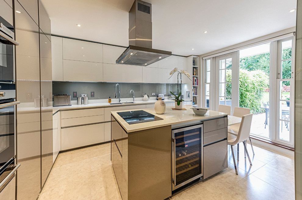 This is an example of a medium sized contemporary l-shaped enclosed kitchen in London with an integrated sink, flat-panel cabinets, white cabinets, composite countertops, grey splashback, glass sheet splashback, stainless steel appliances and an island.