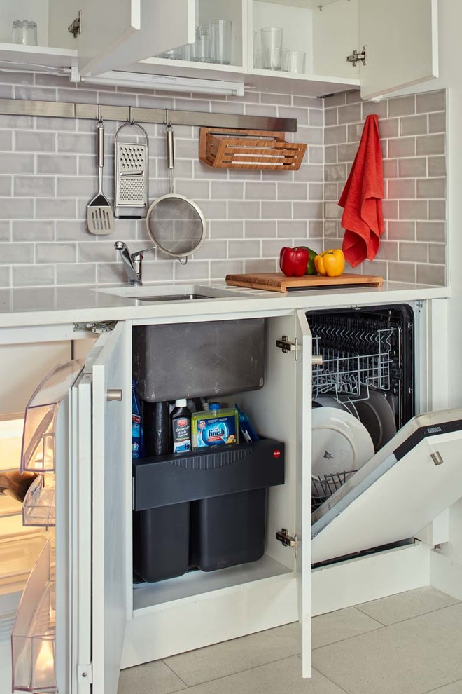 Foto på ett litet funkis kök, med en undermonterad diskho, släta luckor, vita skåp, bänkskiva i kvarts, grått stänkskydd, stänkskydd i tunnelbanekakel, integrerade vitvaror och klinkergolv i keramik
