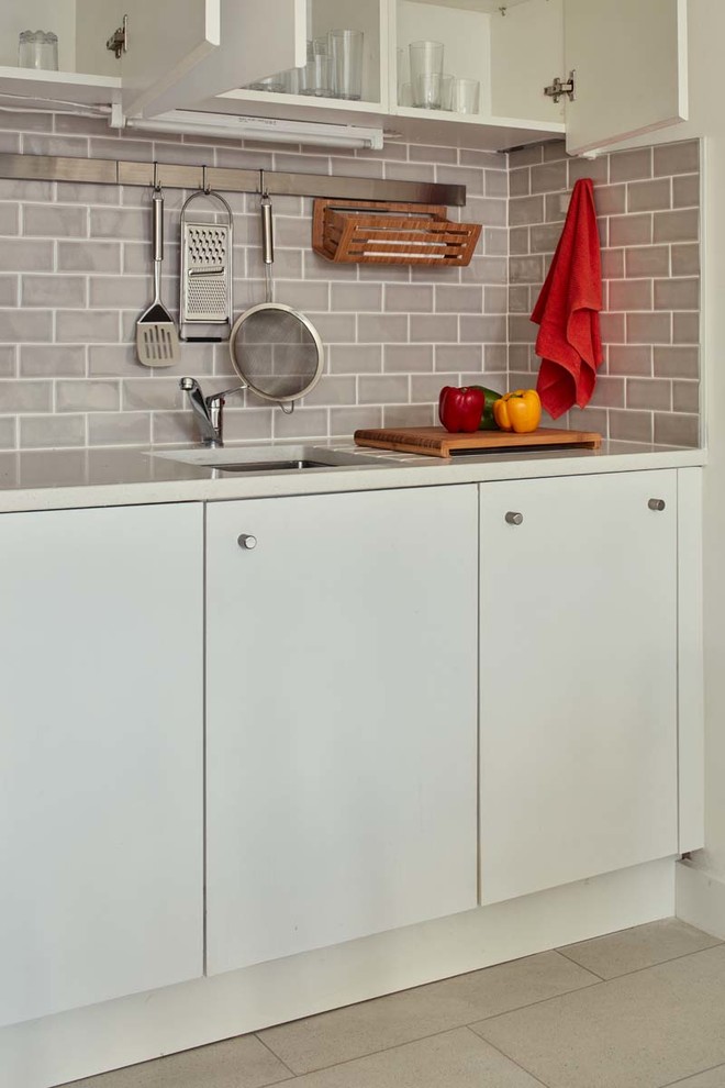 Idéer för att renovera ett litet funkis kök, med en undermonterad diskho, släta luckor, vita skåp, bänkskiva i kvarts, grått stänkskydd, stänkskydd i tunnelbanekakel, integrerade vitvaror och klinkergolv i keramik
