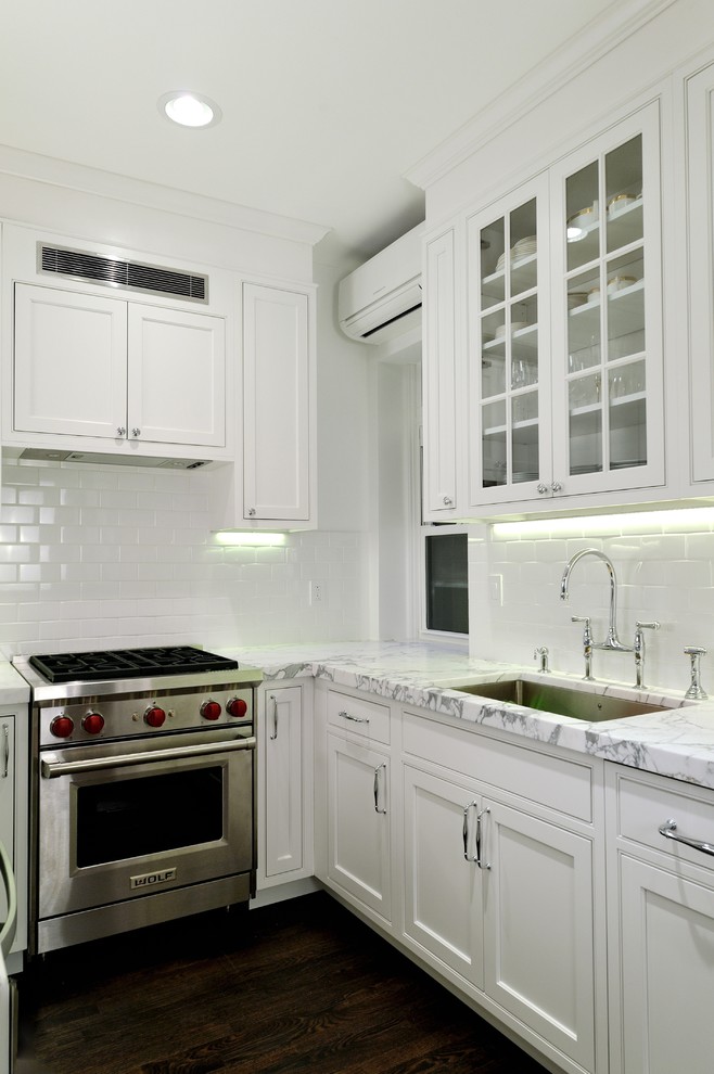 Inredning av ett modernt mellanstort kök, med en enkel diskho, luckor med infälld panel, vita skåp, marmorbänkskiva, vitt stänkskydd, stänkskydd i keramik, rostfria vitvaror och mörkt trägolv