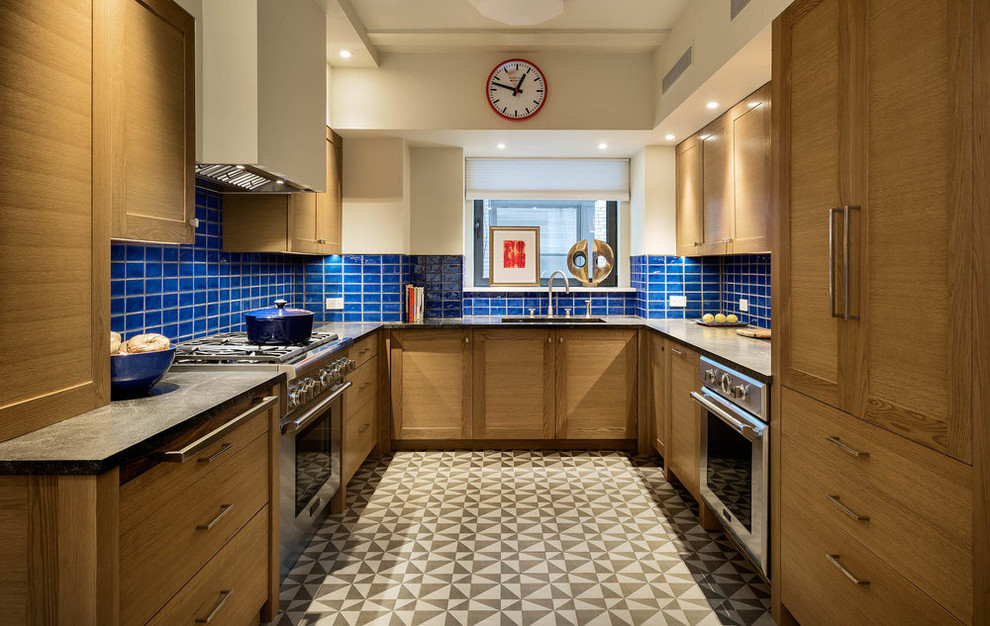 Example of a large transitional u-shaped cement tile floor and multicolored floor kitchen design in New York with shaker cabinets, medium tone wood cabinets, granite countertops, blue backsplash, ceramic backsplash, stainless steel appliances, no island and black countertops