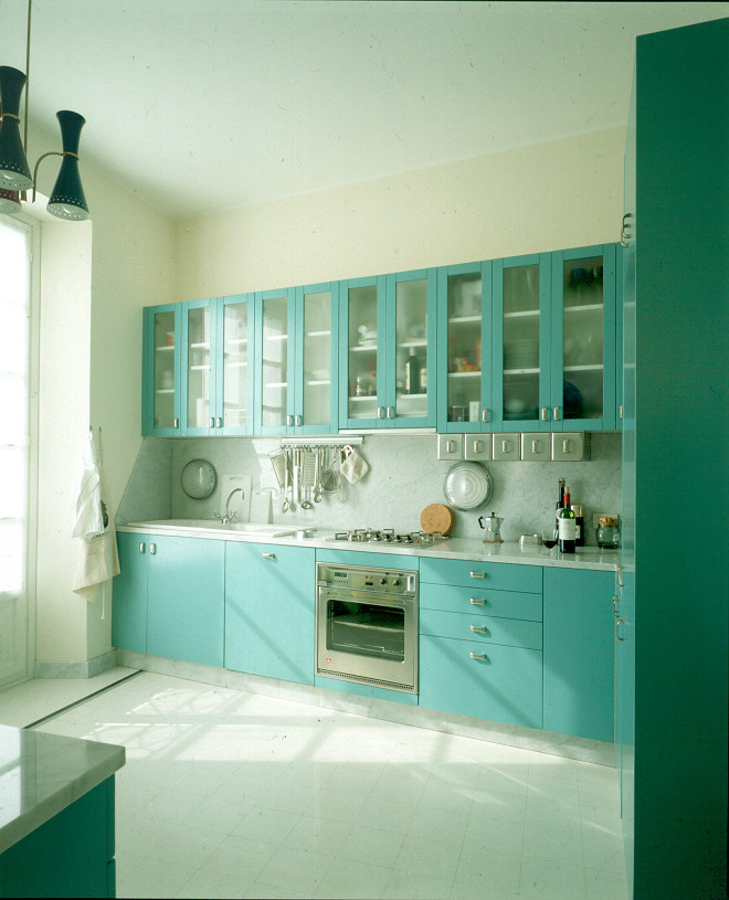 Modelo de cocina moderna con armarios tipo vitrina, puertas de armario turquesas y electrodomésticos de acero inoxidable