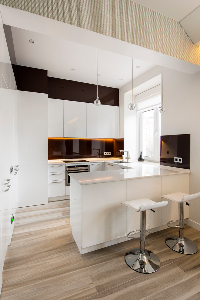 Open concept kitchen - small modern u-shaped medium tone wood floor open concept kitchen idea in Palma de Mallorca with flat-panel cabinets, white cabinets, black backsplash and a peninsula