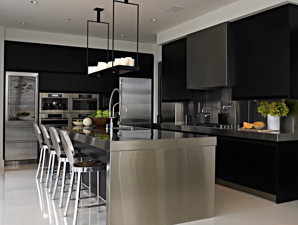 На фото: угловая кухня в современном стиле с плоскими фасадами, черными фасадами, фартуком цвета металлик, техникой из нержавеющей стали и островом