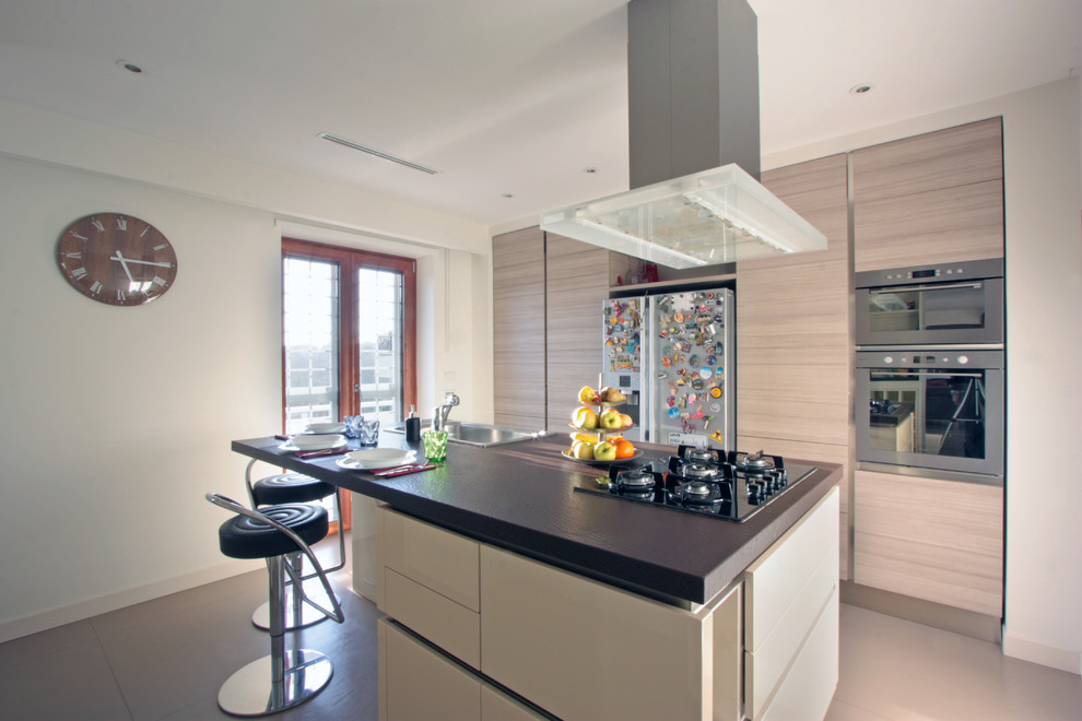 Immagine di una grande cucina moderna con ante beige, elettrodomestici in acciaio inossidabile, pavimento con piastrelle in ceramica, lavello da incasso e ante lisce