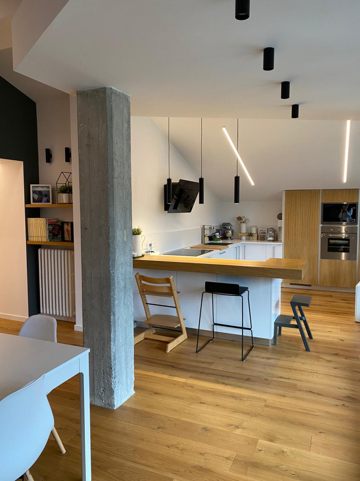 Mid-sized minimalist u-shaped laminate floor and exposed beam eat-in kitchen photo in Other with flat-panel cabinets, light wood cabinets, wood countertops, stainless steel appliances and an island