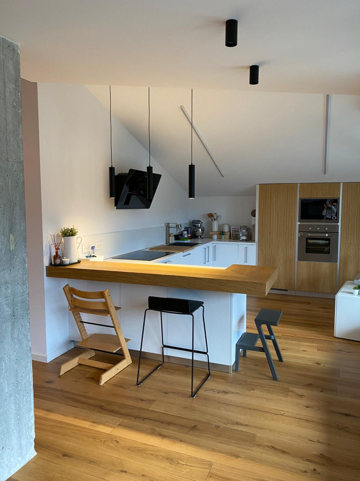 Idee per una cucina minimalista di medie dimensioni con ante lisce, ante in legno chiaro, top in legno, elettrodomestici in acciaio inossidabile, pavimento in laminato e travi a vista