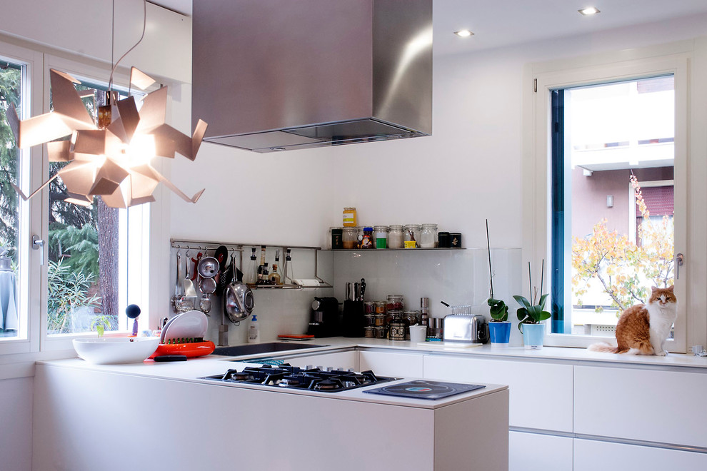 Contemporary u-shaped kitchen in Venice with a single-bowl sink, flat-panel cabinets, white cabinets, composite countertops, white splashback and glass sheet splashback.