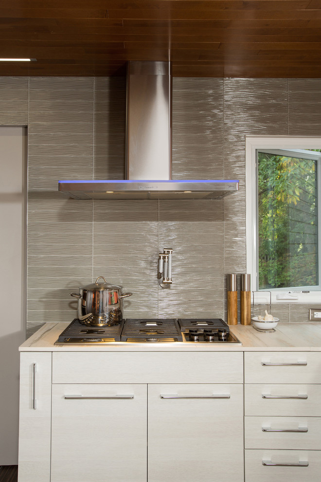 Modern inredning av ett stort kök, med en undermonterad diskho, släta luckor, vita skåp, granitbänkskiva, grått stänkskydd, stänkskydd i keramik, rostfria vitvaror, klinkergolv i keramik och en köksö