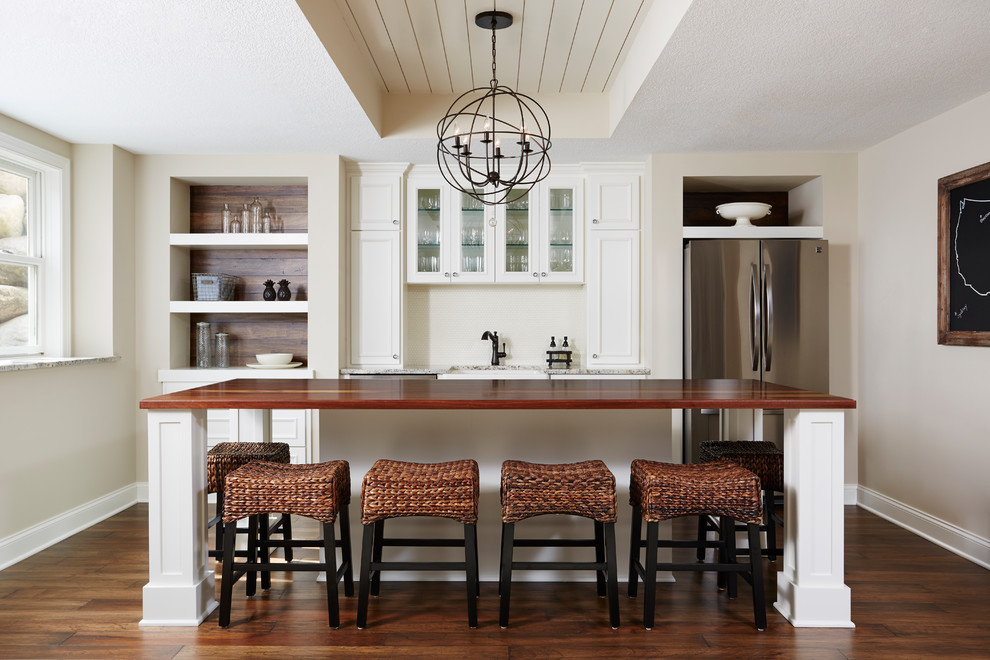 Foto di una cucina country di medie dimensioni con pavimento in legno massello medio, pavimento marrone, ante in stile shaker, ante bianche, paraspruzzi bianco e elettrodomestici in acciaio inossidabile