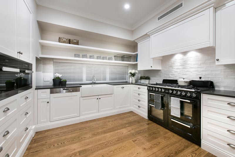 Photo of a classic u-shaped kitchen in Perth with a belfast sink, recessed-panel cabinets, white cabinets, white splashback, stainless steel appliances and medium hardwood flooring.