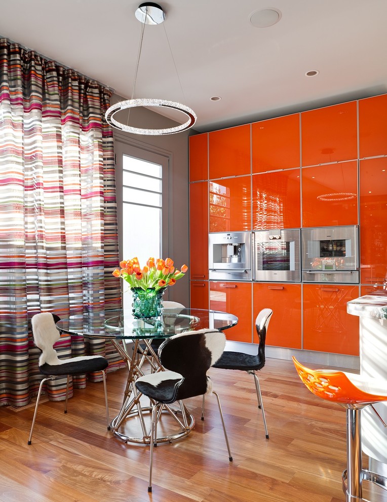 Modern inredning av ett kök och matrum, med släta luckor, orange skåp, mellanmörkt trägolv och en köksö