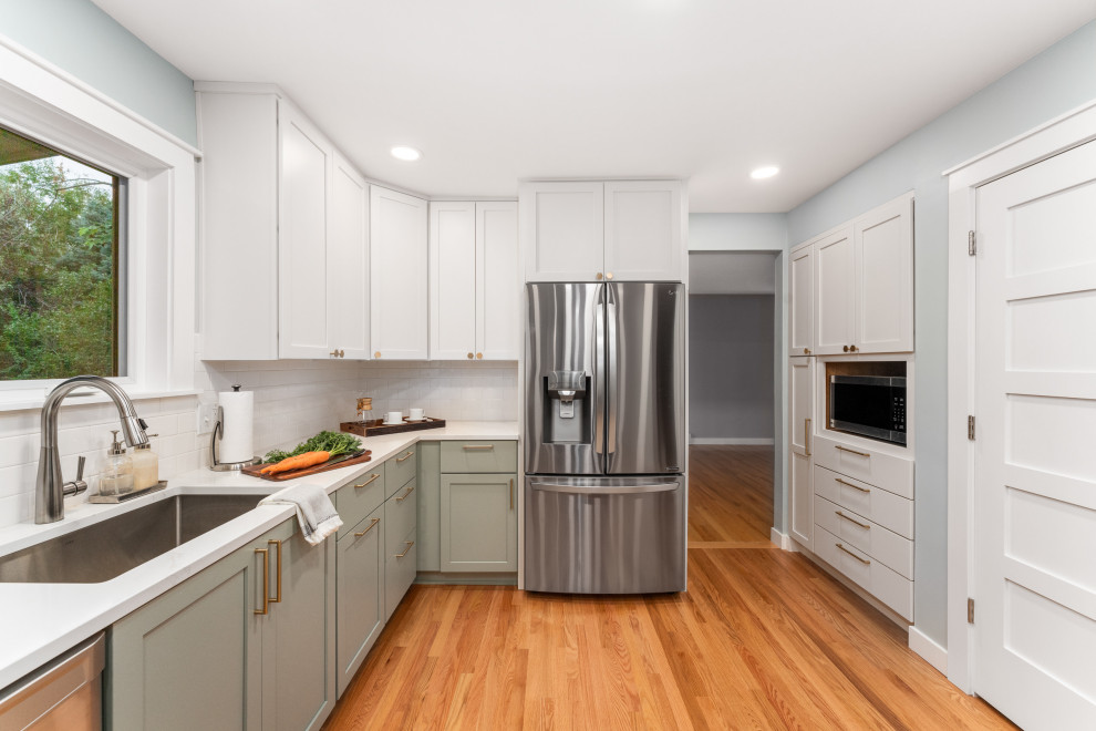 Example of a mid-sized transitional u-shaped medium tone wood floor and brown floor enclosed kitchen design in Denver with an undermount sink, shaker cabinets, green cabinets, quartz countertops, white backsplash, subway tile backsplash, stainless steel appliances, no island and white countertops