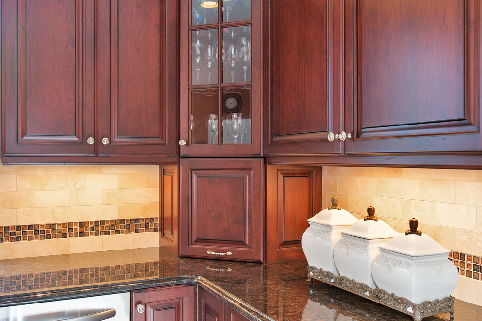 Klassisk inredning av ett kök, med en undermonterad diskho, luckor med upphöjd panel, skåp i mörkt trä, granitbänkskiva, beige stänkskydd, stänkskydd i stenkakel och rostfria vitvaror