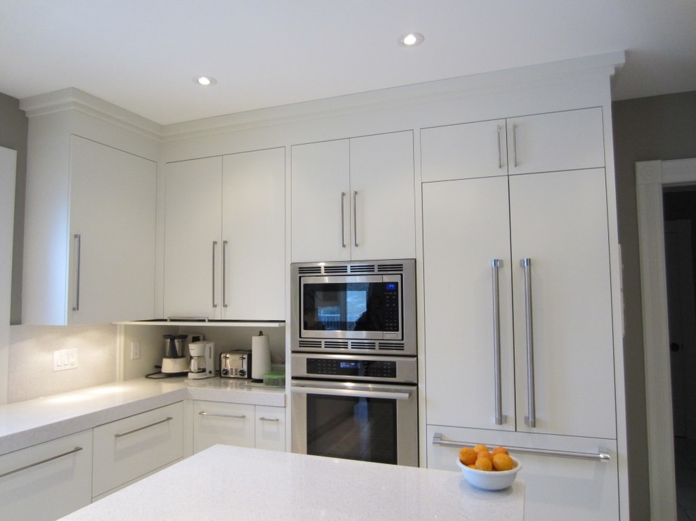 Ejemplo de cocina actual con armarios con paneles lisos, puertas de armario blancas, encimera de cuarzo compacto y electrodomésticos de acero inoxidable