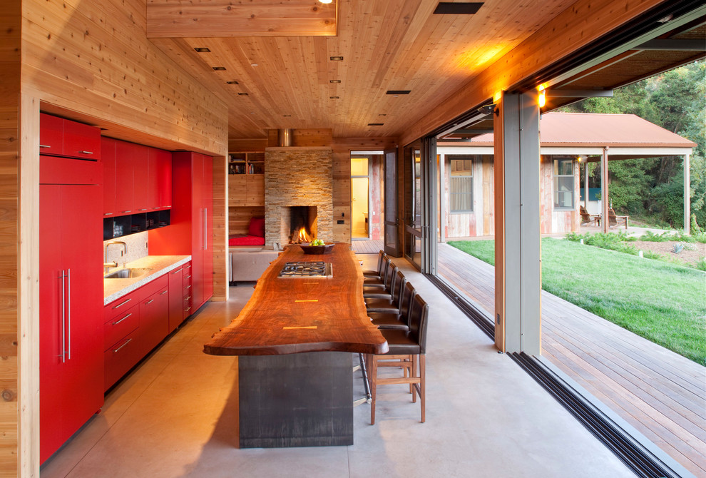 На фото: прямая кухня среднего размера в стиле модернизм с красными фасадами, техникой под мебельный фасад, обеденным столом, накладной мойкой, бежевым фартуком и островом с
