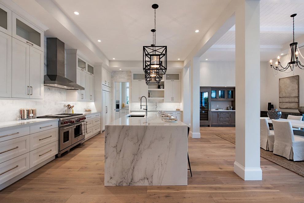Inspiration for a contemporary l-shaped open plan kitchen in Miami with a submerged sink, recessed-panel cabinets, white cabinets, stainless steel appliances, medium hardwood flooring, brown floors, white worktops and an island.