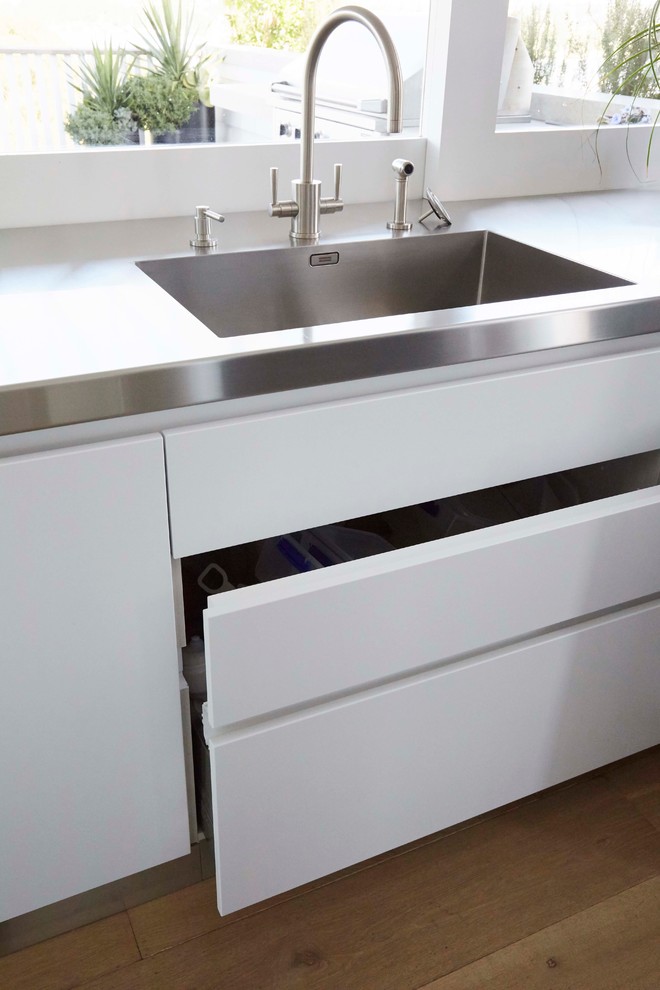 Große Moderne Wohnküche mit integriertem Waschbecken, weißen Schränken, Edelstahl-Arbeitsplatte, Küchengeräten aus Edelstahl, braunem Holzboden und Kücheninsel in Sydney