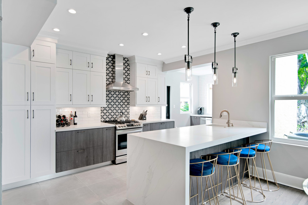 Mid-sized transitional u-shaped porcelain tile and gray floor open concept kitchen photo in Miami with a farmhouse sink, shaker cabinets, white cabinets, quartz countertops, stainless steel appliances, a peninsula and white countertops