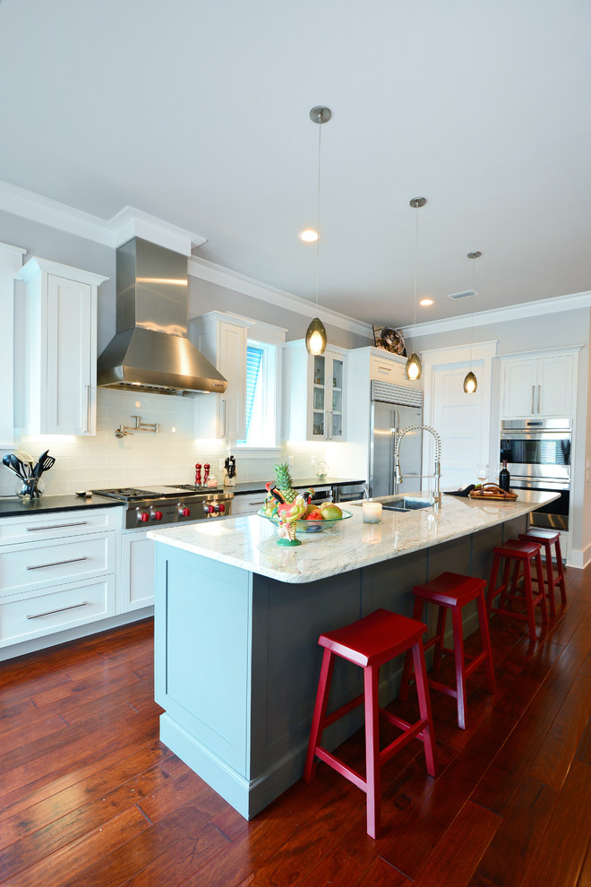 Klassische Küche mit Doppelwaschbecken, Schrankfronten im Shaker-Stil, weißen Schränken, Küchenrückwand in Weiß, dunklem Holzboden und Kücheninsel in Miami