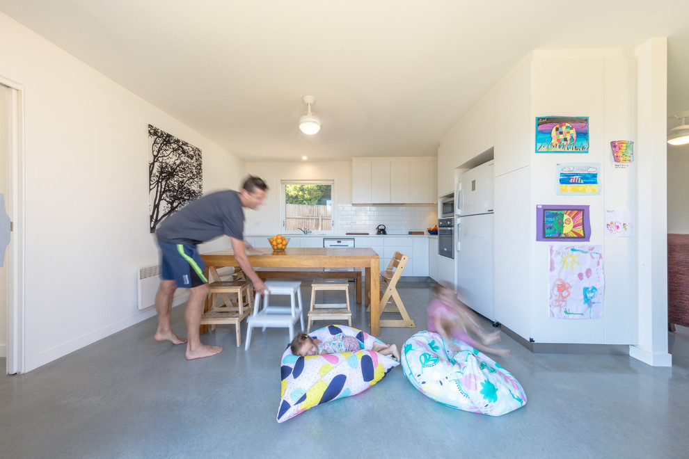 Small trendy l-shaped concrete floor and gray floor eat-in kitchen photo in Canberra - Queanbeyan with flat-panel cabinets, white cabinets, laminate countertops, white backsplash, cement tile backsplash, stainless steel appliances, no island and white countertops