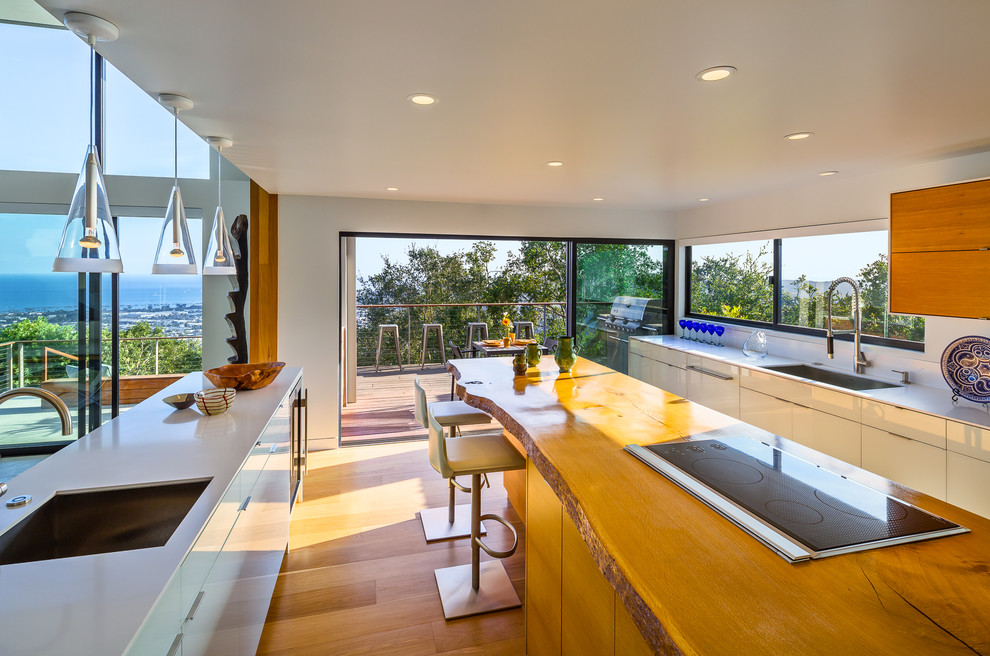 Immagine di una cucina contemporanea con lavello sottopiano, ante lisce, ante bianche, pavimento in legno massello medio e 2 o più isole