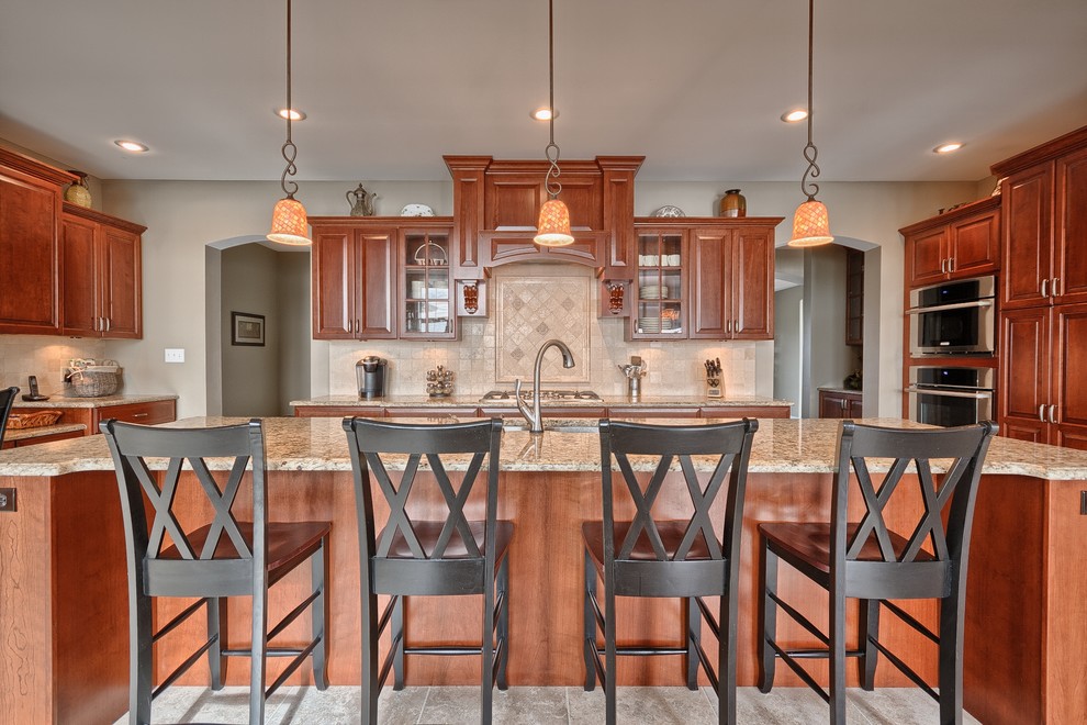 Eat-in kitchen - large traditional galley ceramic tile and gray floor eat-in kitchen idea in St Louis with a drop-in sink, raised-panel cabinets, medium tone wood cabinets, wood countertops, beige backsplash, ceramic backsplash, stainless steel appliances and an island