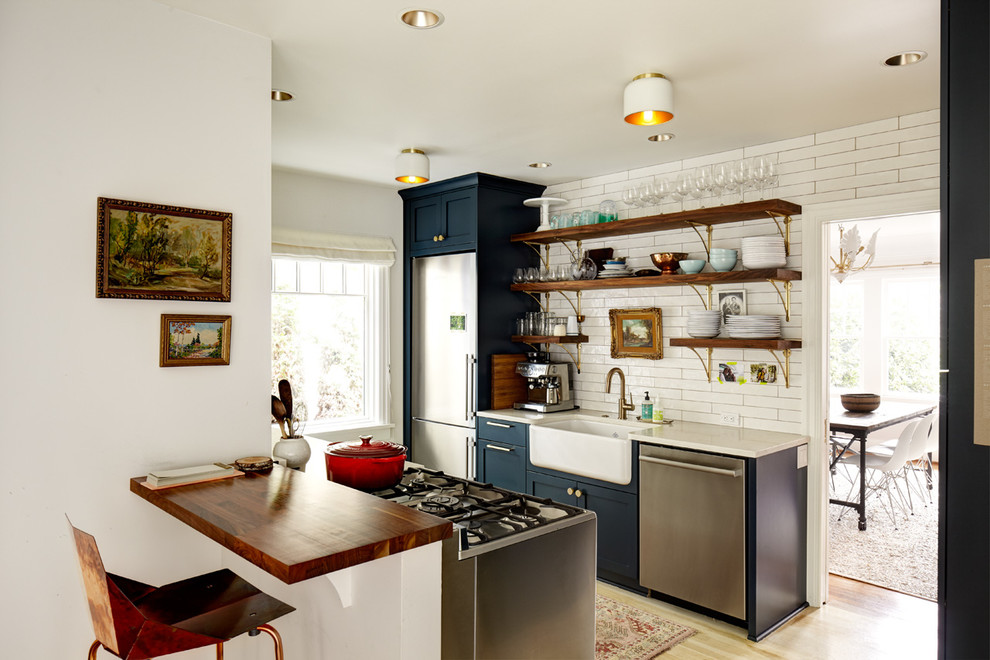 Inspiration for a country galley light wood floor enclosed kitchen remodel in Seattle with a farmhouse sink, open cabinets, blue cabinets, white backsplash, stainless steel appliances and no island