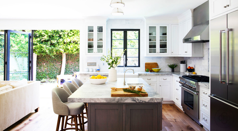 Inredning av ett medelhavsstil stort grå grått kök, med en rustik diskho, skåp i shakerstil, vita skåp, marmorbänkskiva, grått stänkskydd, stänkskydd i marmor, rostfria vitvaror, mellanmörkt trägolv, en köksö och brunt golv